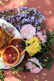 a plate of pancakes, orange slices, and flowers