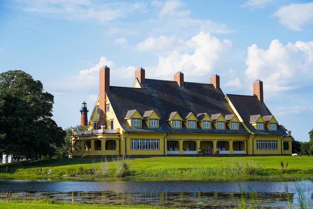 Braunes und weißes Betonhaus in der Nähe des Flusses unter weißen Wolken tagsüber