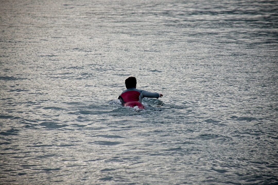 person in red shirt swimming on water during daytime