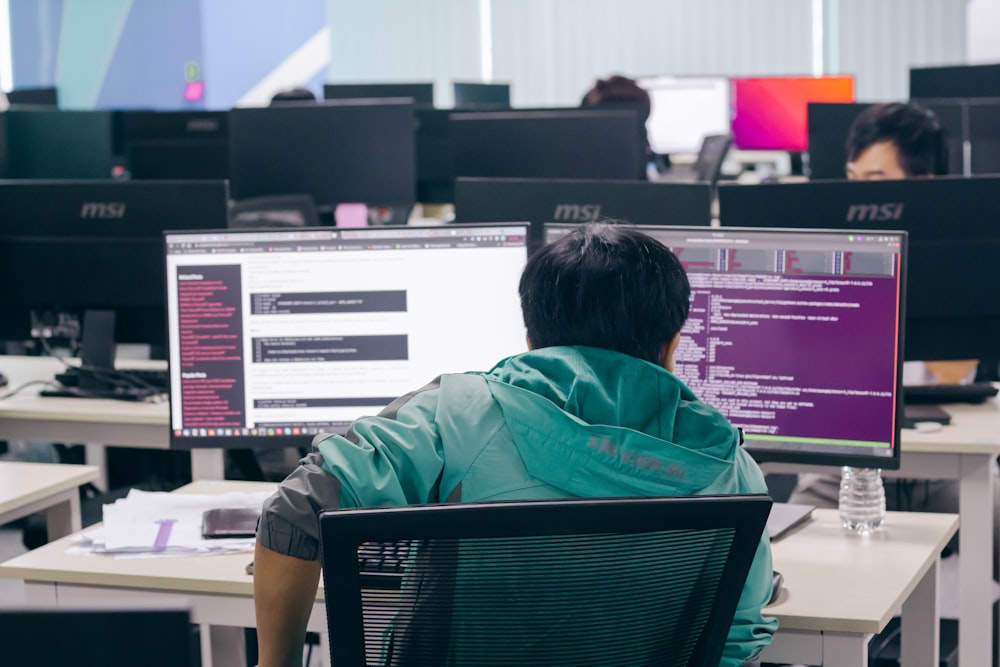 a man sitting in front of two computer monitors