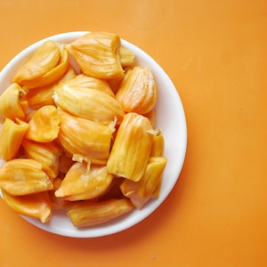 sliced yellow fruit in white ceramic bowl