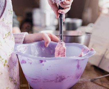 person holding stainless steel spoon and clear glass bowl