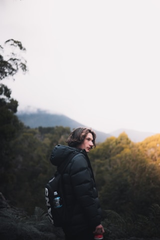 woman in black jacket standing on mountain during daytime
