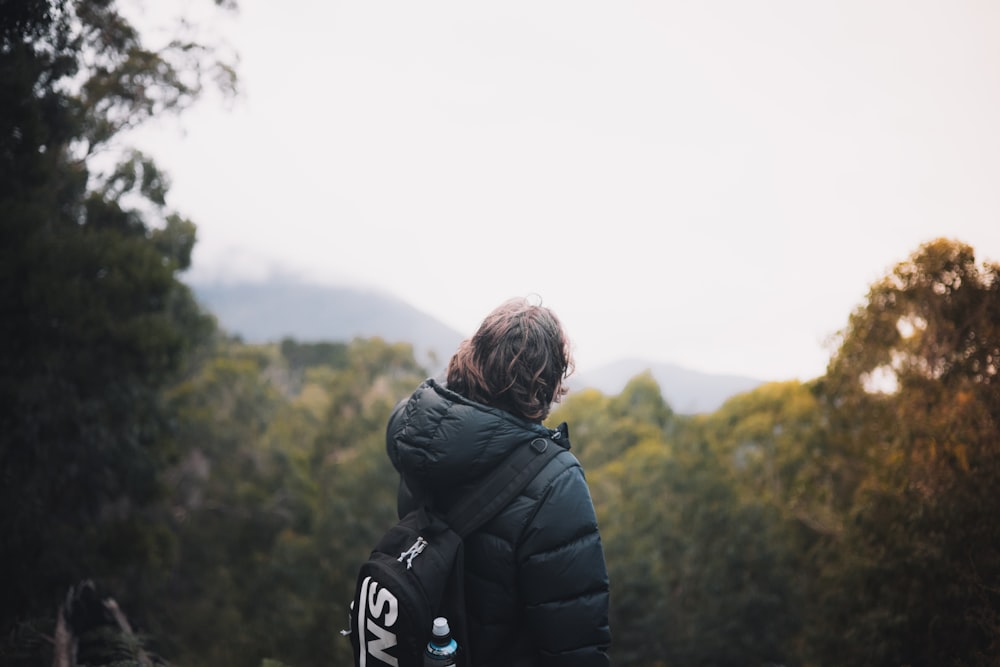 woman in black jacket standing on green grass field during daytime