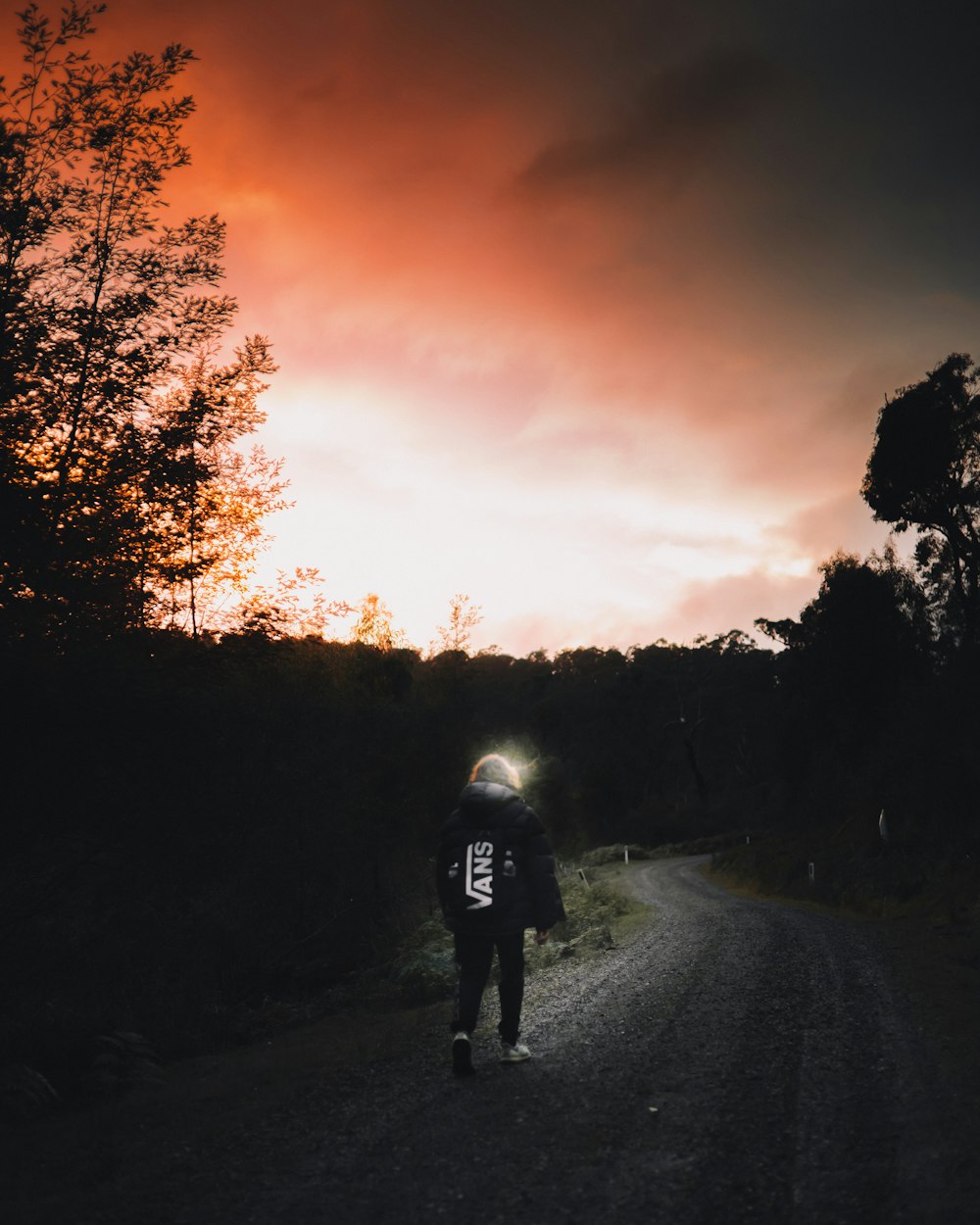 uomo in giacca nera che cammina sulla strada durante il tramonto