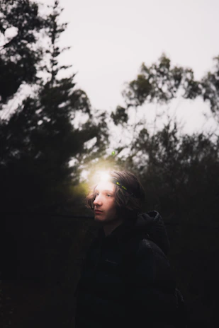 Low-light shot of a person wearing Noxvigil gear navigating through a misty urban forest at dusk.