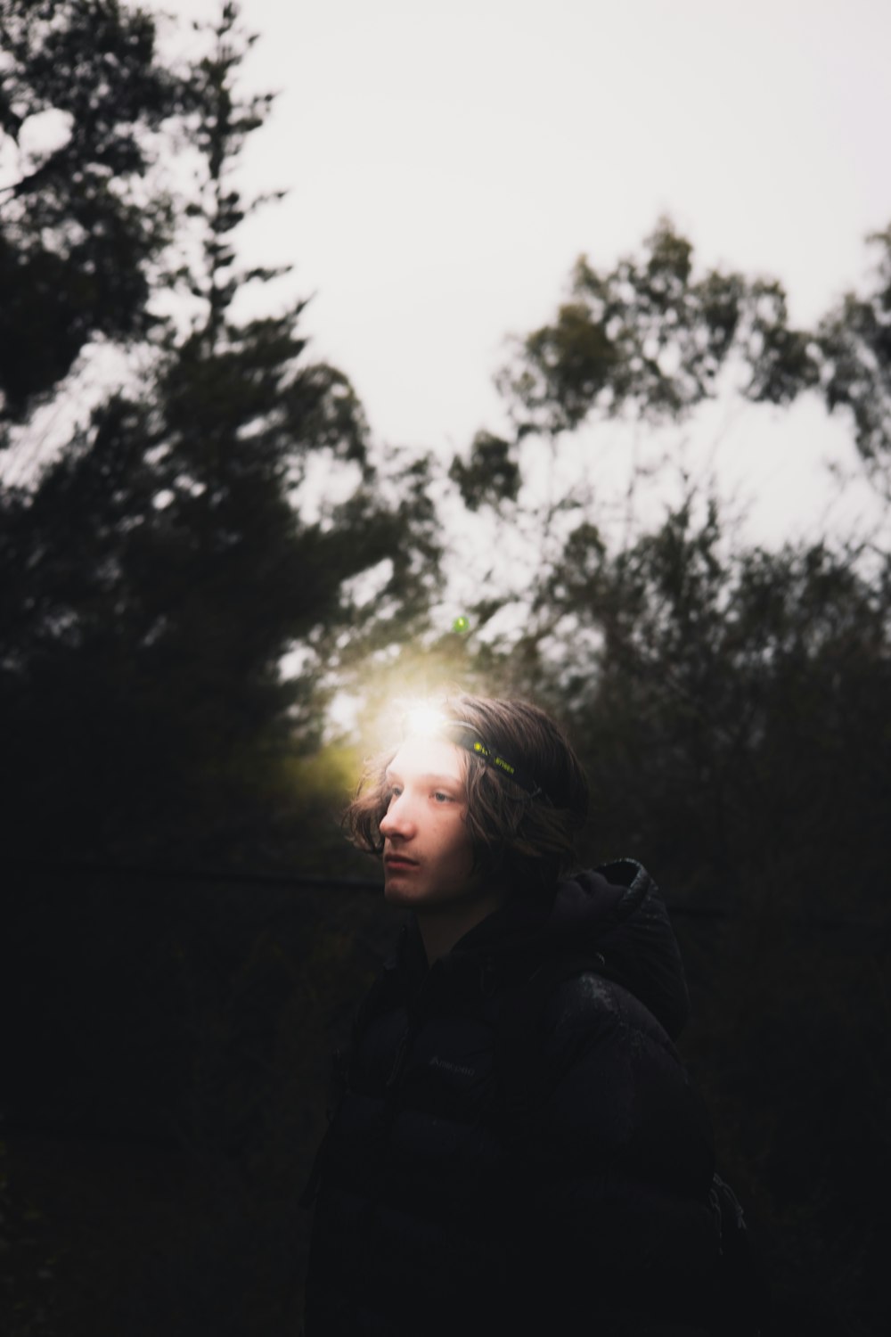 woman in black jacket standing near trees during daytime