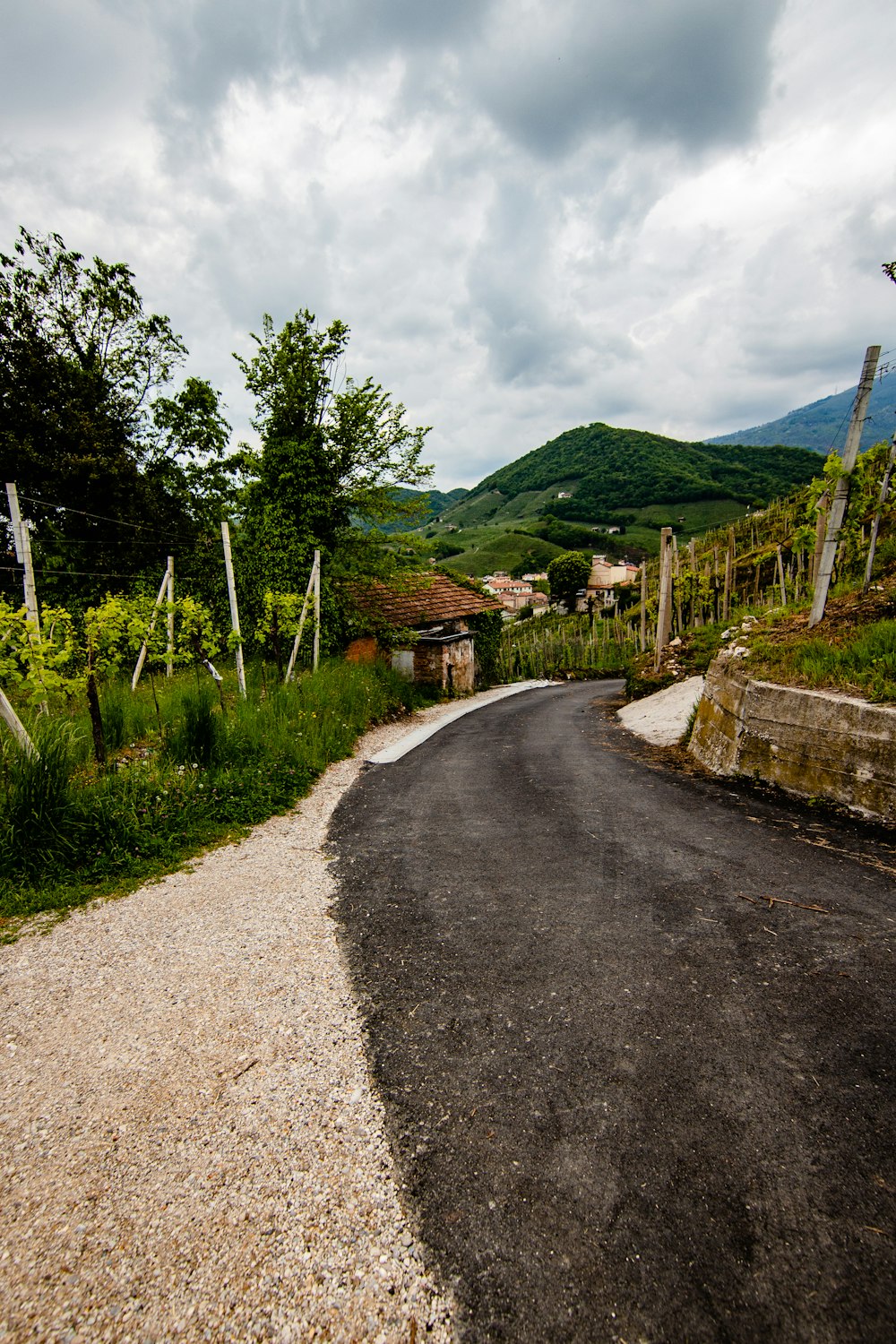 gray concrete road between green grass field under white cloudy sky during daytime