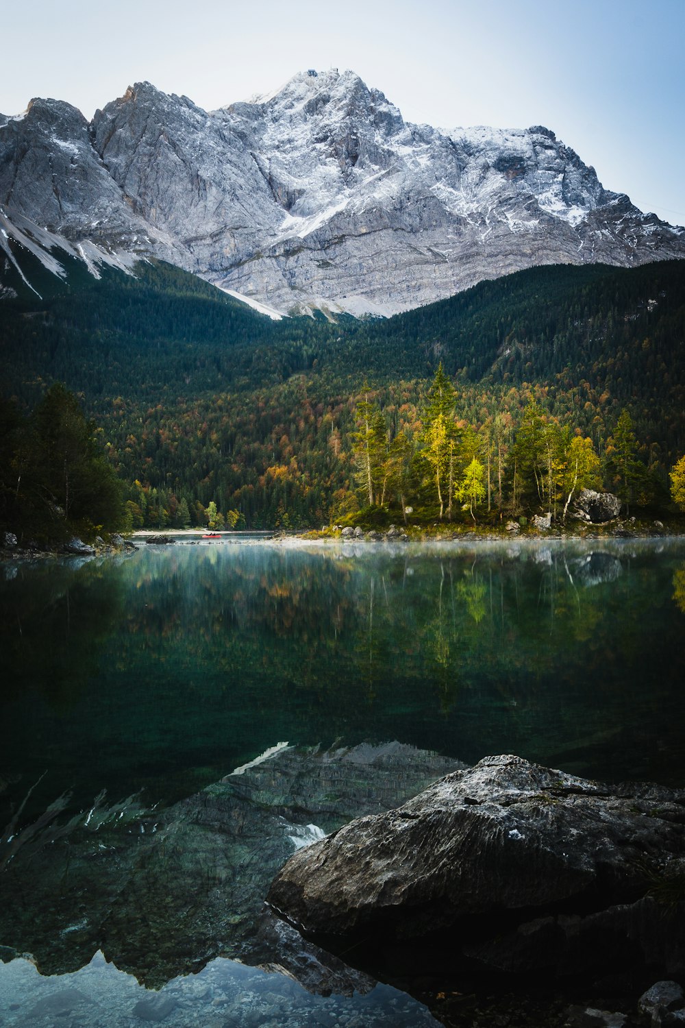 árvores verdes perto do lago e da montanha coberta de neve durante o dia