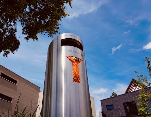 Close-up of a modern metal trash bin with a park background.