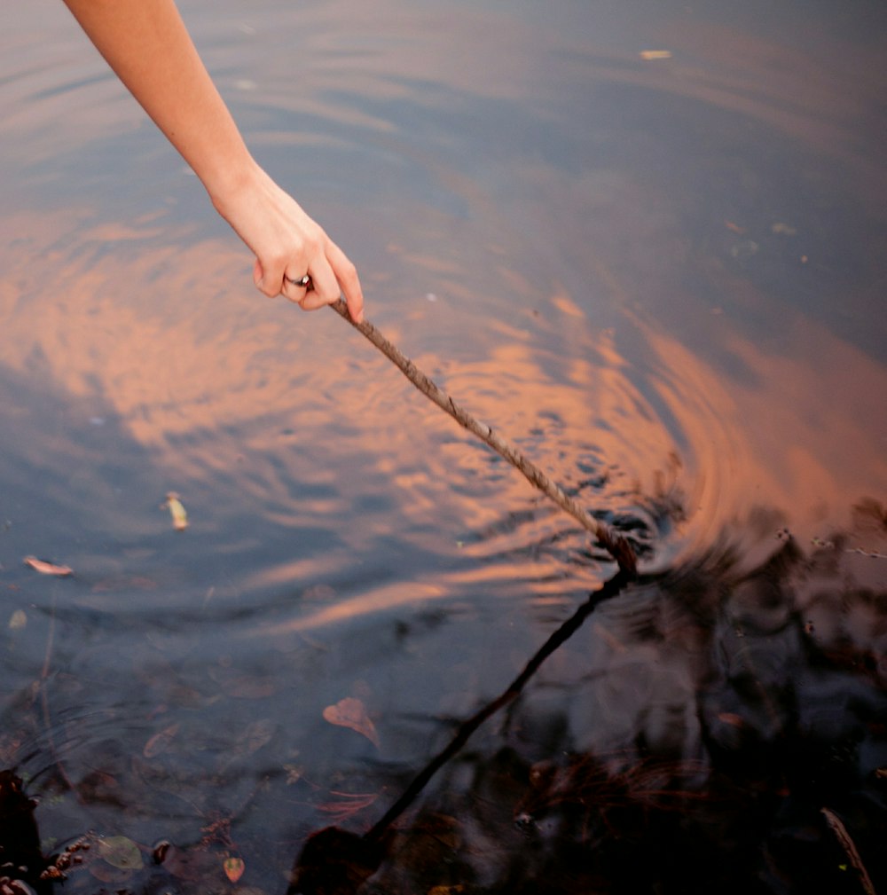 person holding black rope on body of water during daytime