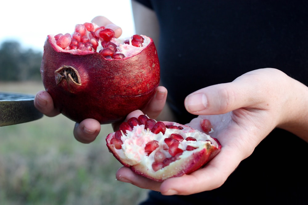 person holding red pomegranate fruit