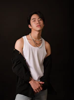 Model wearing a sleek Annili t-shirt with layered gold necklaces, standing against a soft off-white backdrop.