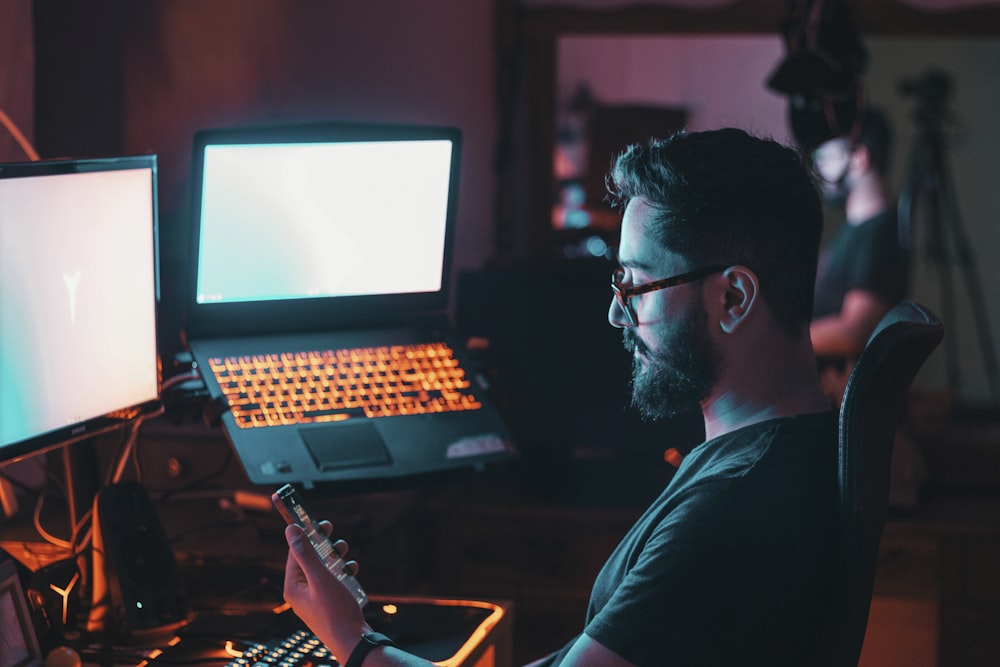 man in blue shirt wearing black framed eyeglasses using black laptop computer