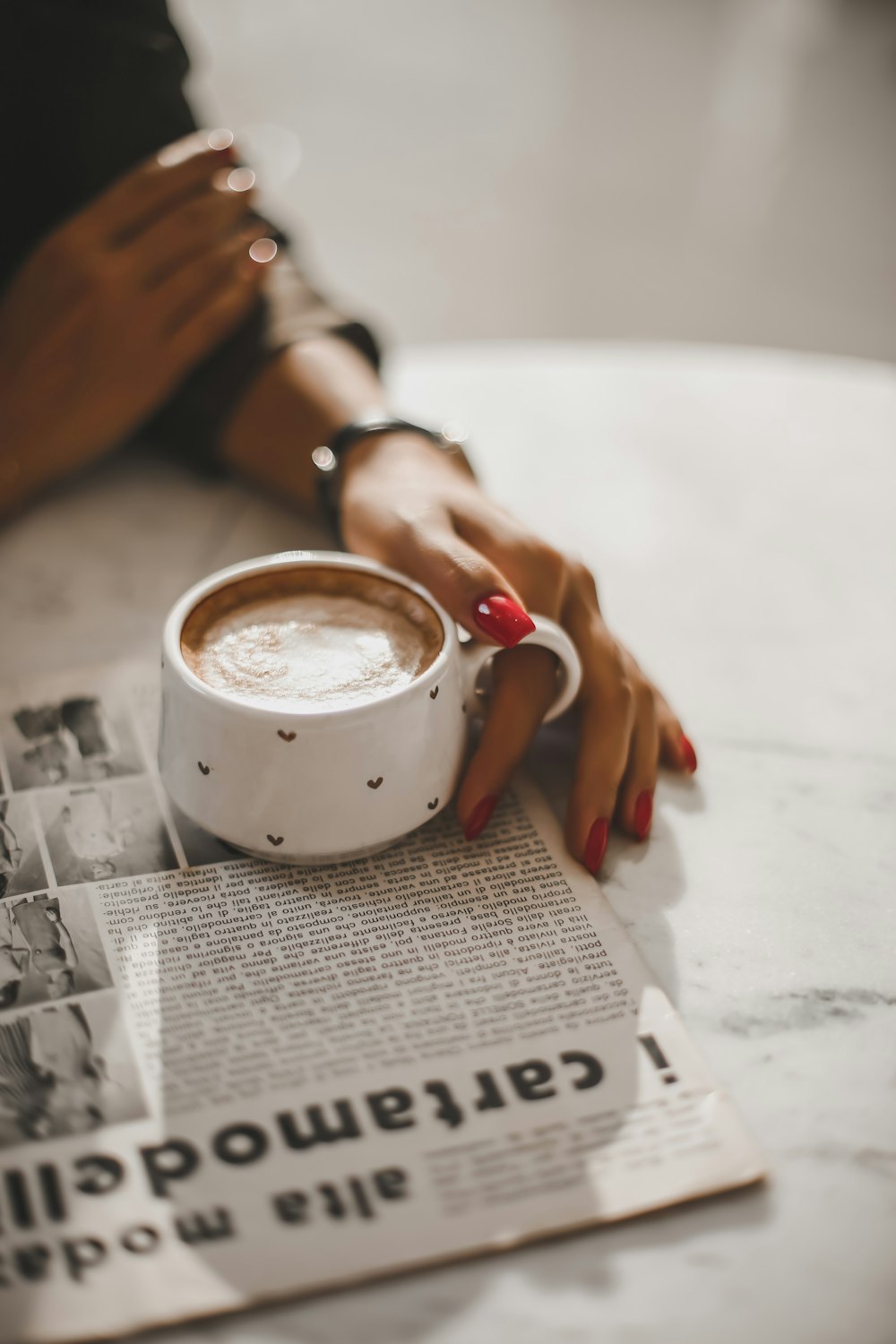 persona sosteniendo una taza de cerámica blanca con café