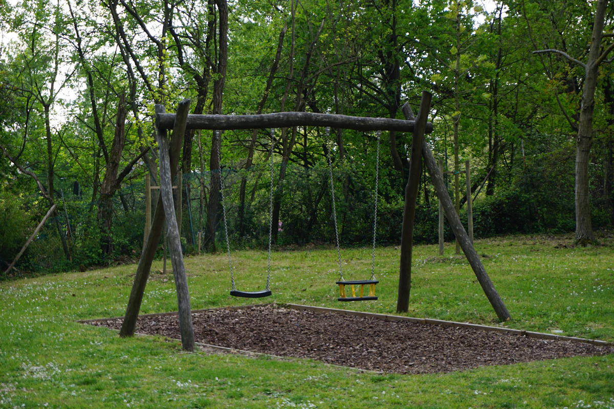 Columpios de madera en un jardín rodeado de árboles