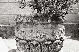 Close-up of a handcrafted stone planter with delicate metal accents, nestled among lush greenery.