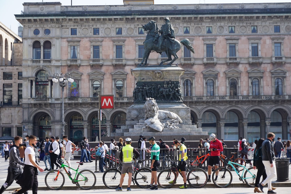 people riding bicycles on road near white concrete building during daytime