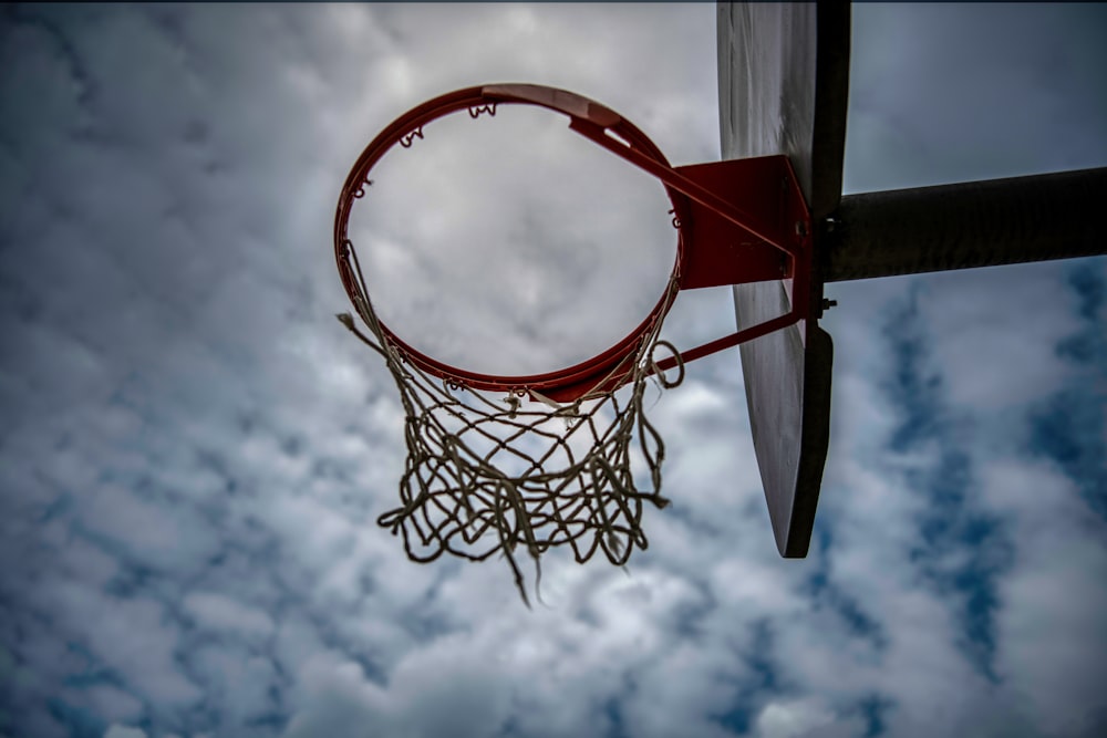 red and white basketball hoop under white clouds and blue sky during daytime