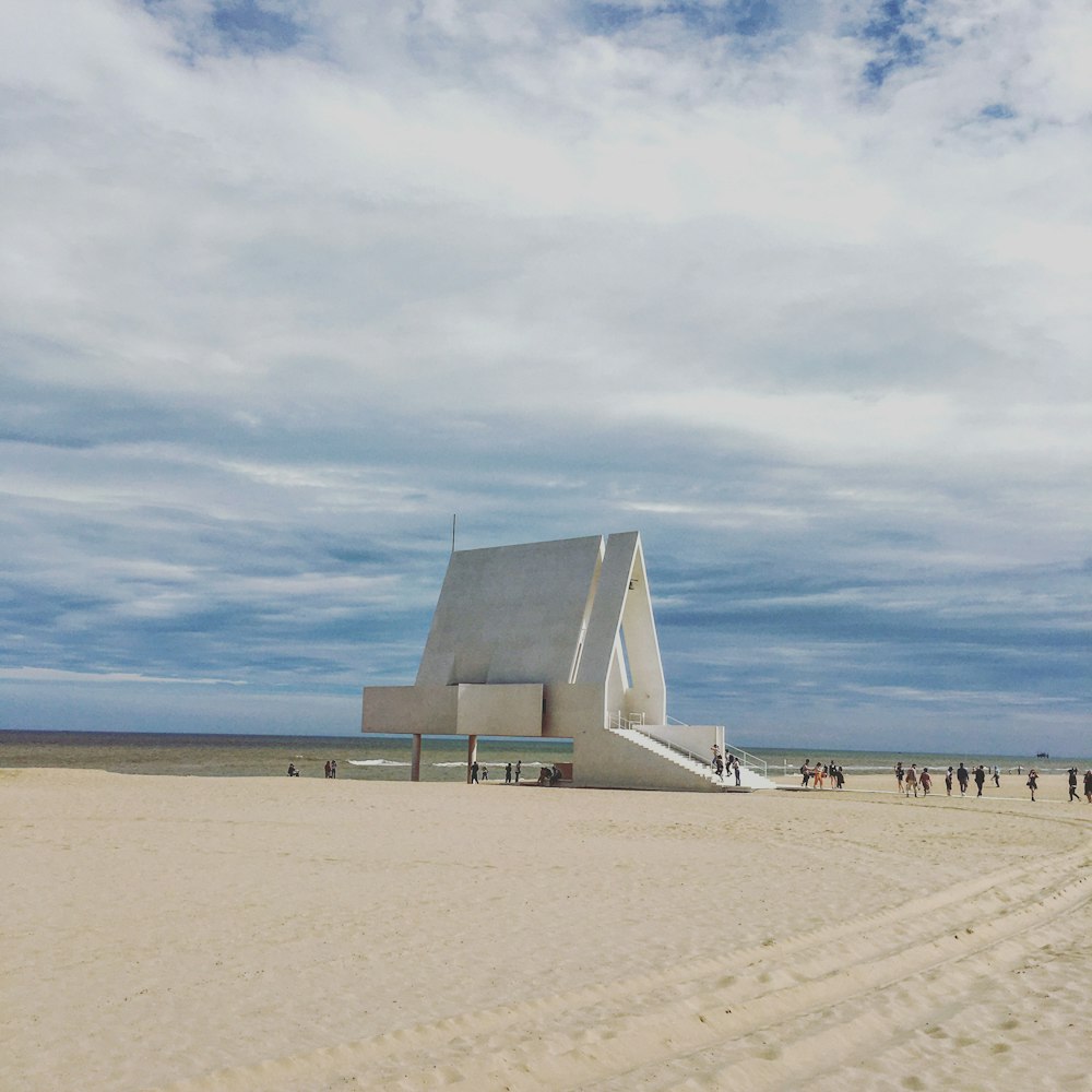 Weißer Betonbau auf braunem Sand unter weißen Wolken tagsüber