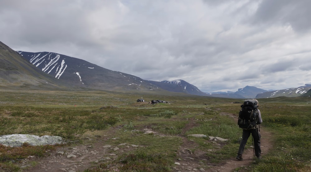 green grass field near mountain under white clouds during daytime