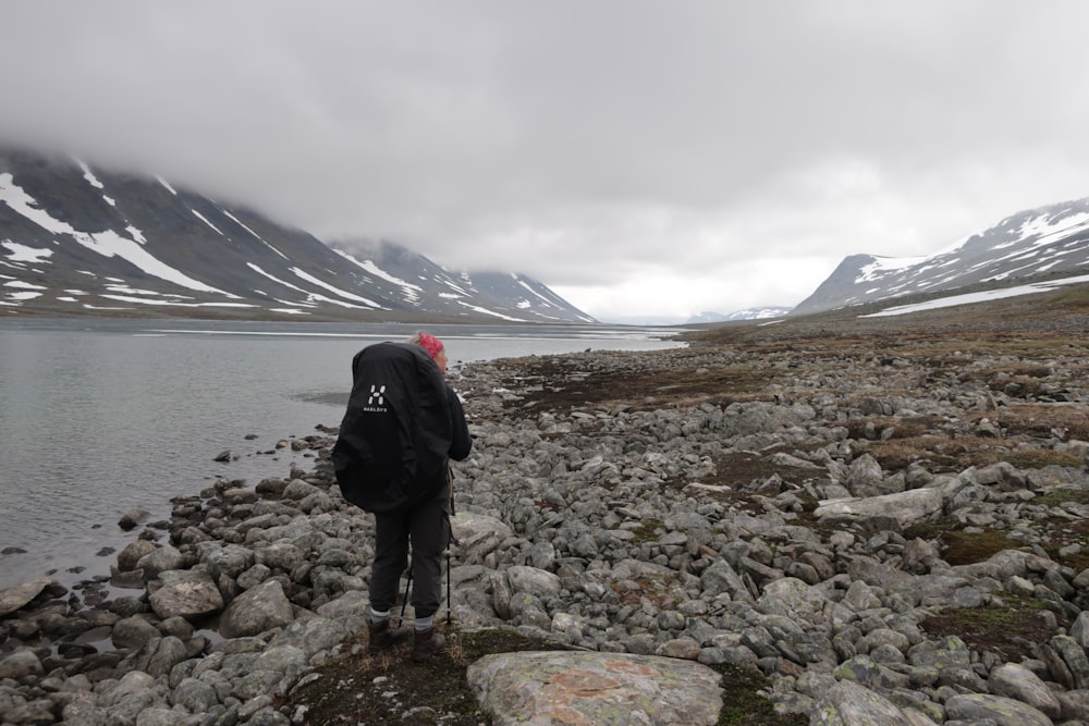 person in black jacket standing on rocky shore during daytime