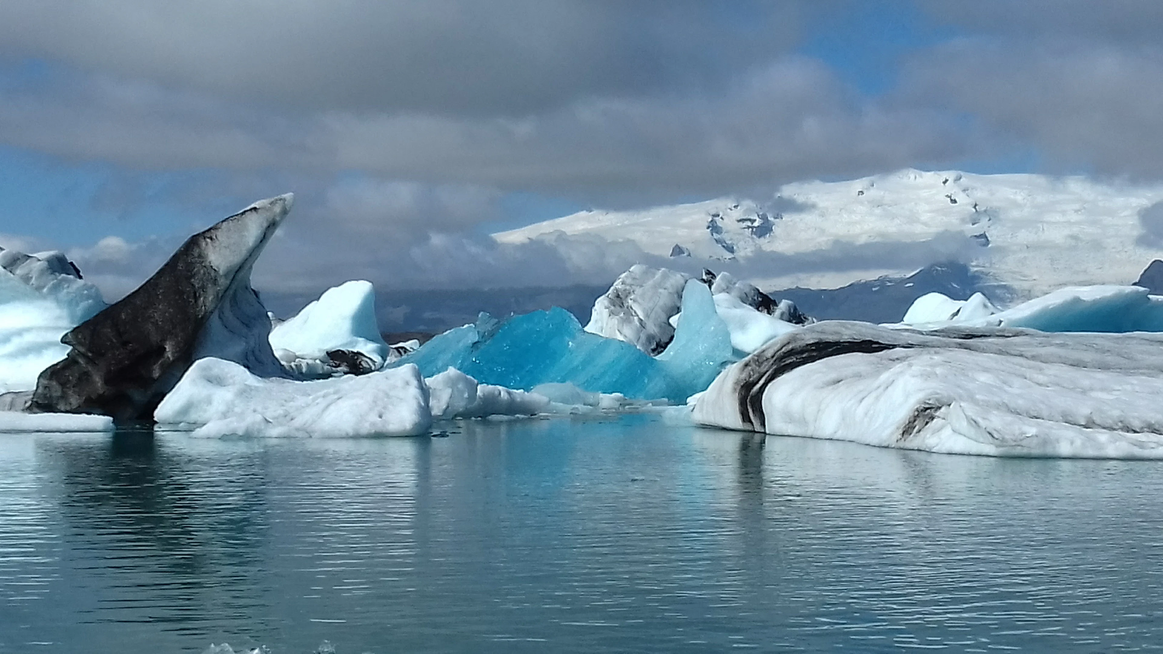 Blue and white icebergs drifting in the Jökulsárlón glacier lagoon, with a snow-covered glacier behind