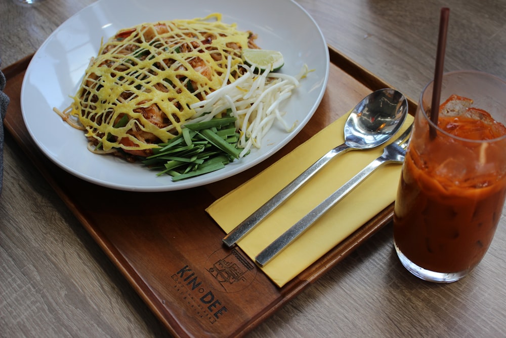 pasta on white ceramic plate beside stainless steel fork and spoon