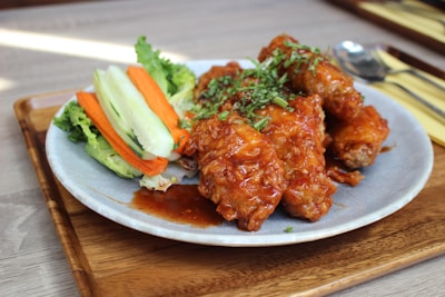 A plate of fried chicken wings glazed with a tangy sauce, garnished with fresh herbs.