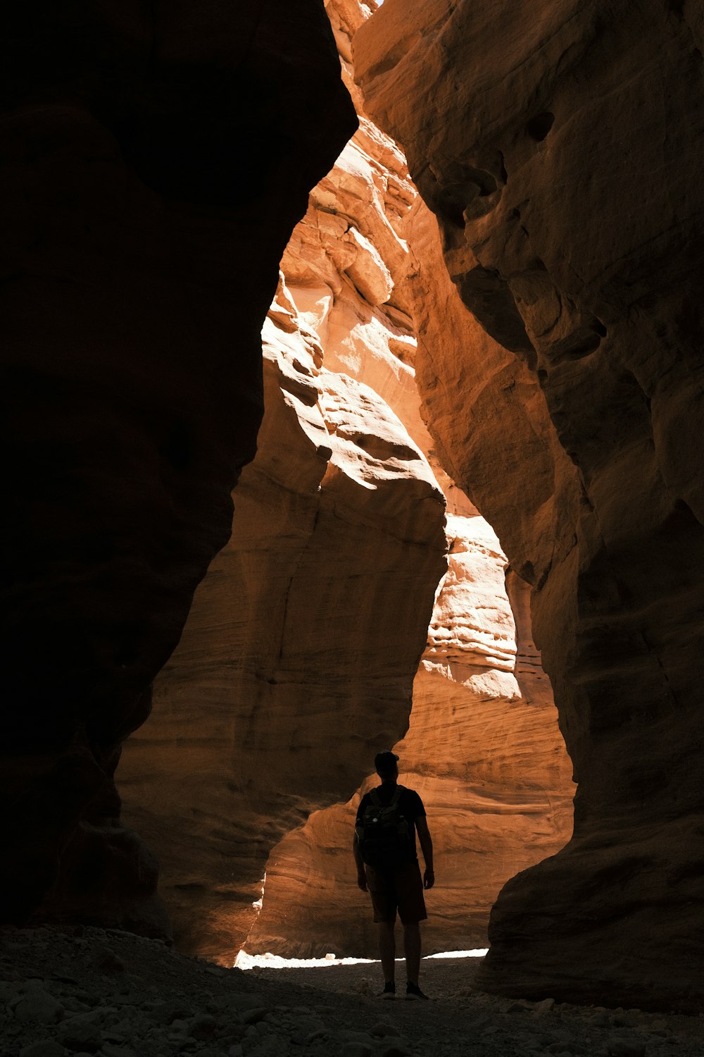 man in black jacket standing on brown rock formation during daytime