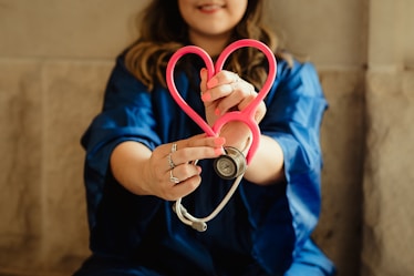 girl in blue jacket holding red and silver ring