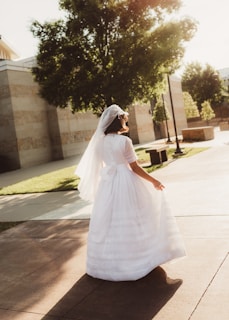woman in white dress walking on sidewalk during daytime