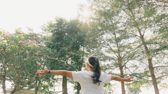 woman in white t-shirt standing on tree branch during daytime