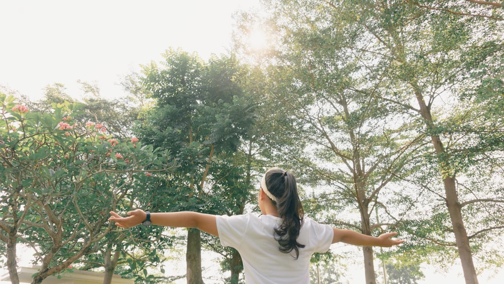 femme en t-shirt blanc debout sur une branche d’arbre pendant la journée