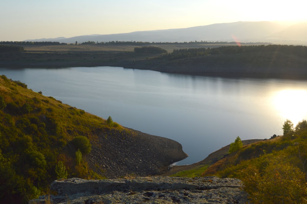 green mountain beside body of water during daytime