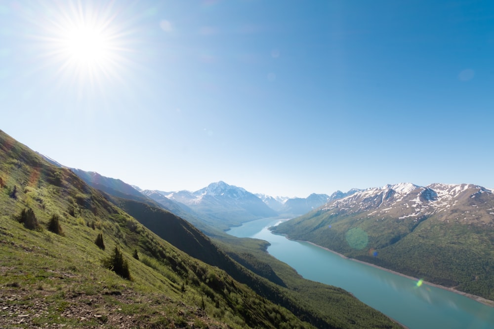 Montagnes vertes près du lac sous le ciel bleu pendant la journée