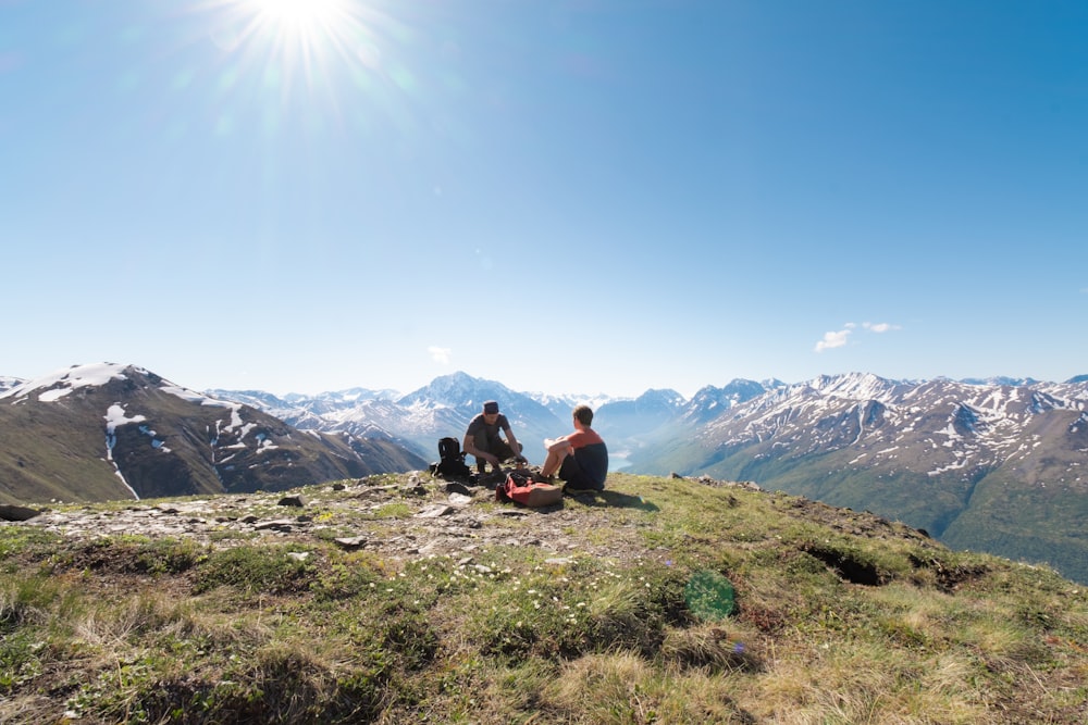 2 men sitting on green grass field during daytime