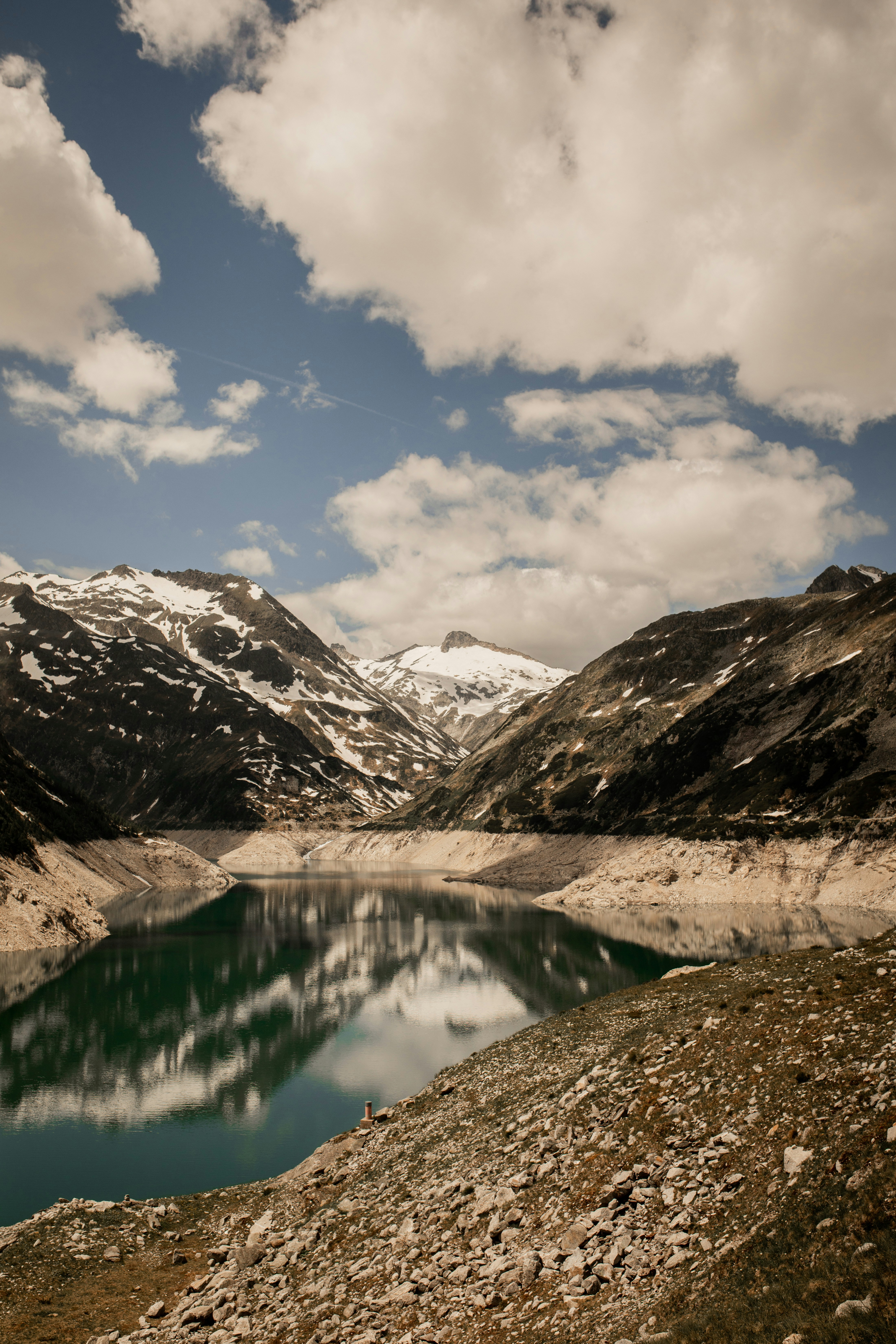 lake in the middle of snow covered mountains under blue sky and white clouds during daytime