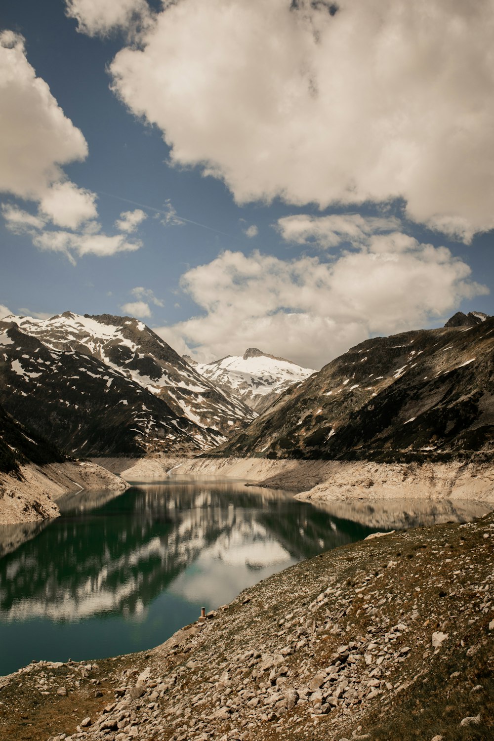 lake in the middle of snow covered mountains under blue sky and white clouds during daytime