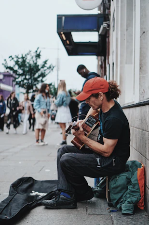 man in black t-shirt playing brown acoustic guitar