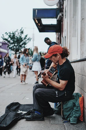 man in black t-shirt playing brown acoustic guitar