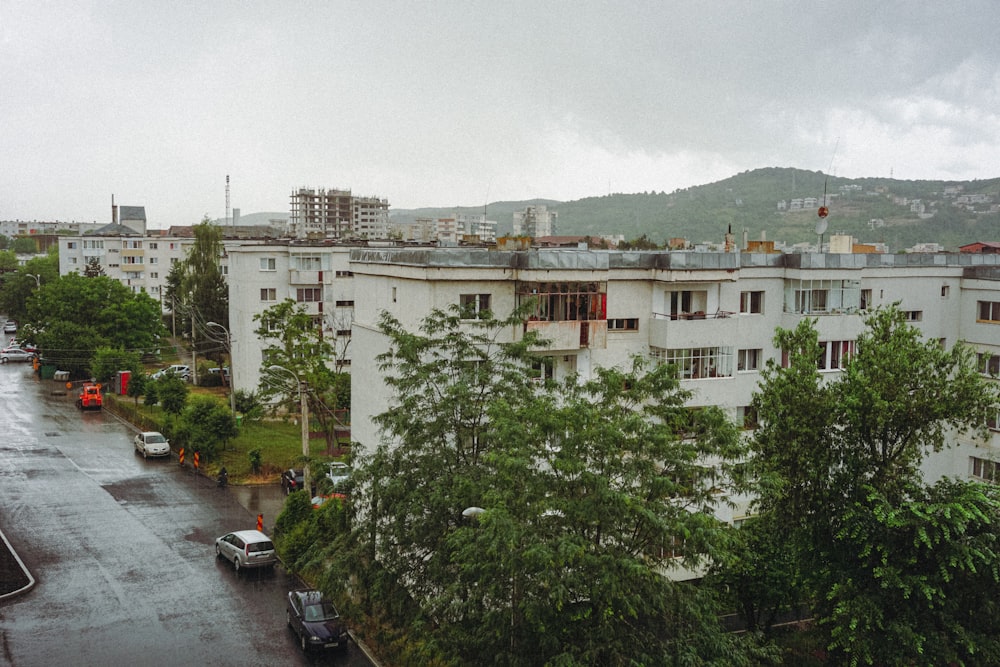 cars parked near green trees and white concrete building during daytime