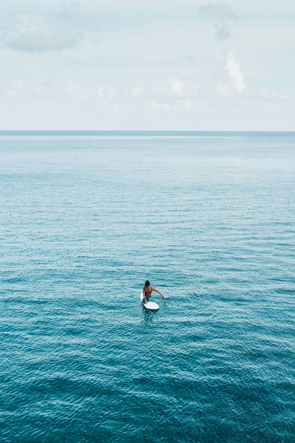 woman in white shirt and black pants surfing on sea during daytime