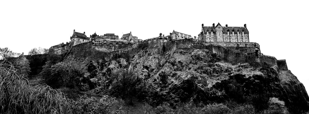 grayscale photo of castle on cliff