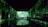 A dark, immersive space with vivid green projections covering the walls and ceiling, resembling a natural, forest-like setting. Silhouettes of people stand on a bridge, creating reflections in the water below.