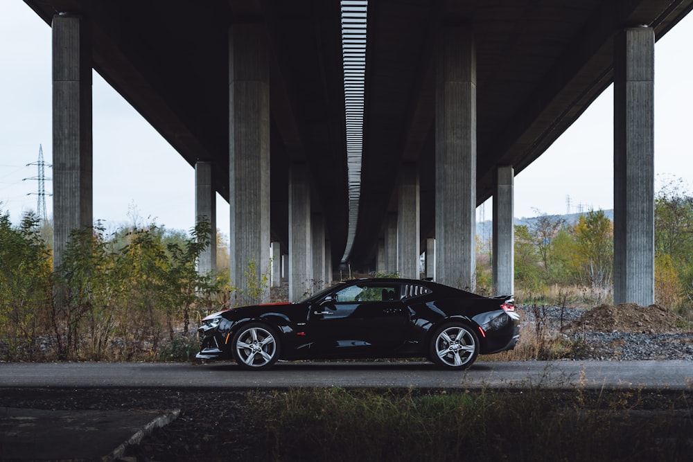 black coupe parked under bridge during daytime