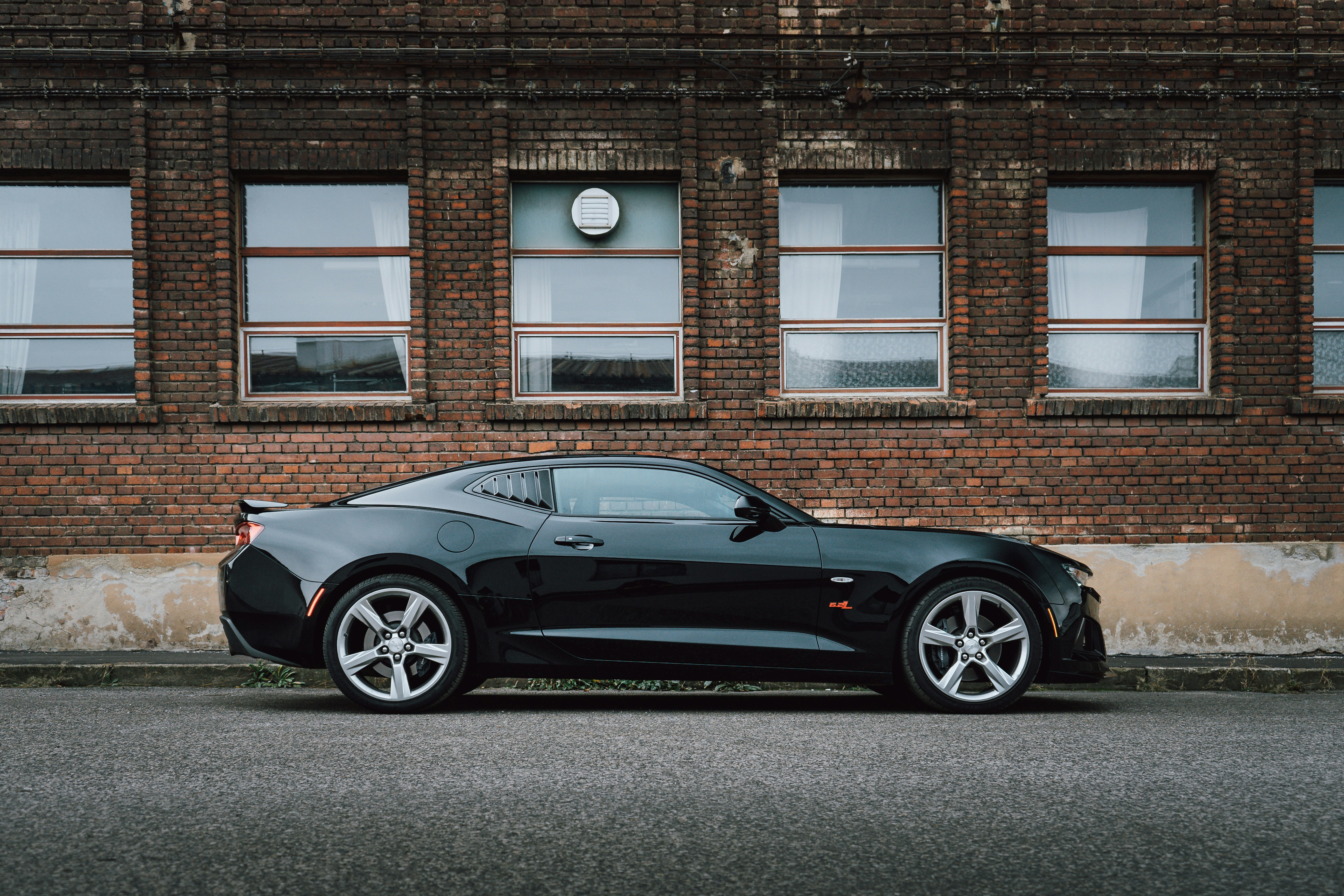 black porsche 911 parked in front of brown brick building
