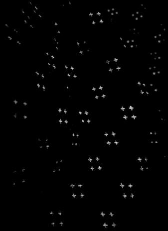 A pattern of small, star-shaped light points scattered randomly across a dark background, creating a night sky effect.