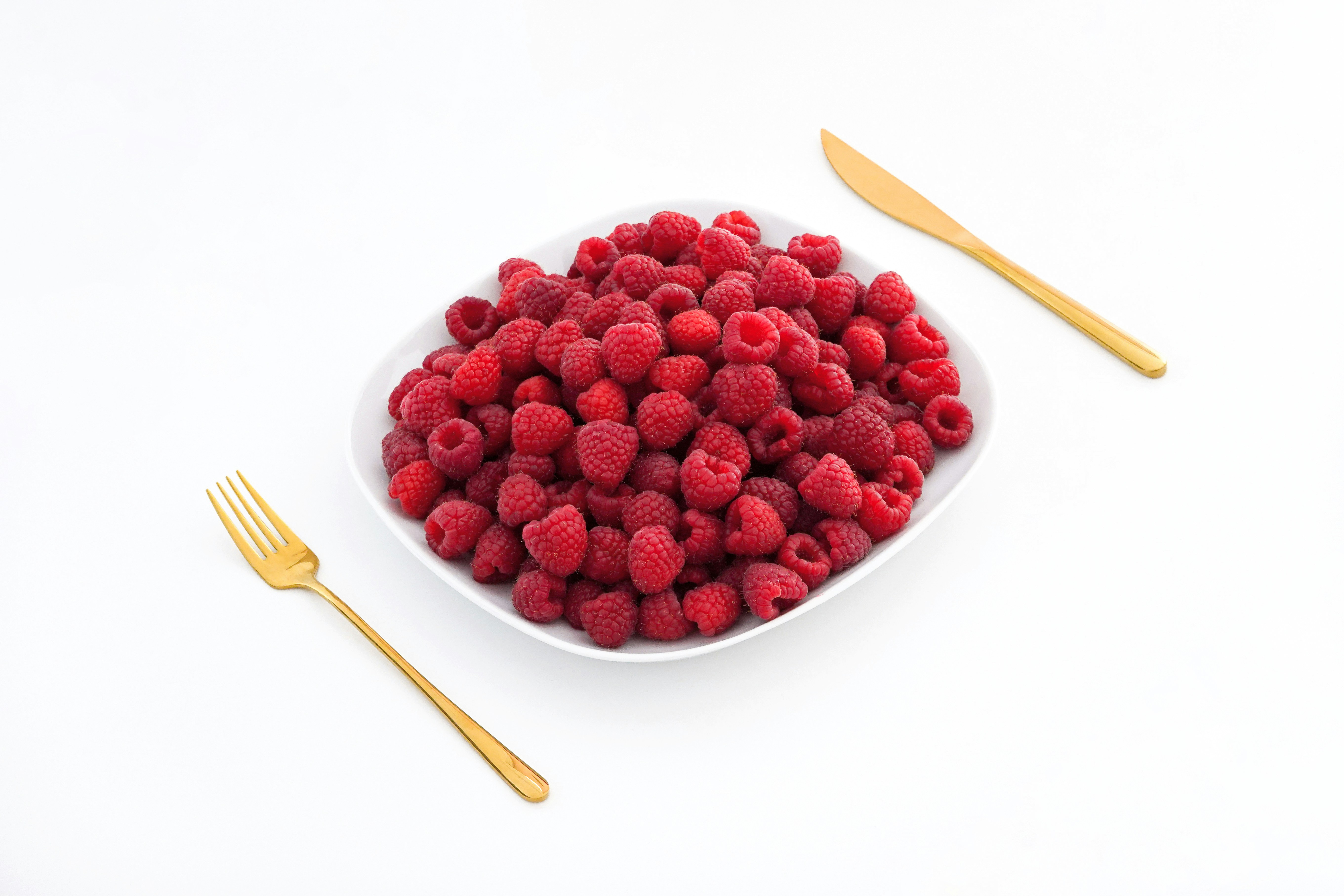 red raspberries on white ceramic bowl