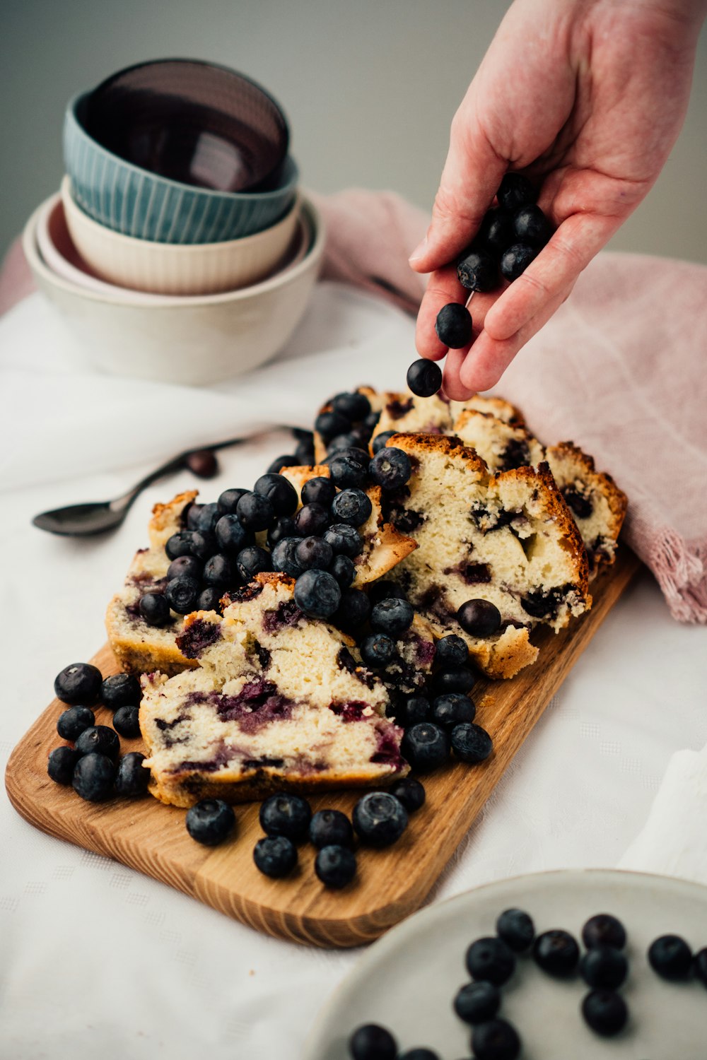 person holding brown wooden chopping board with black berries